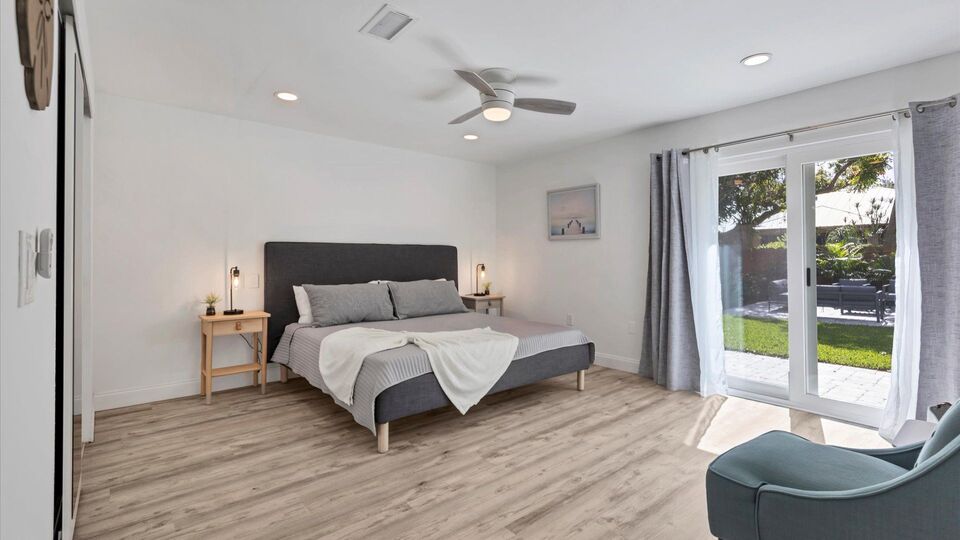 Primary bedroom with king bed, attached bathroom, access to backyard, and 50-inch Smart TV