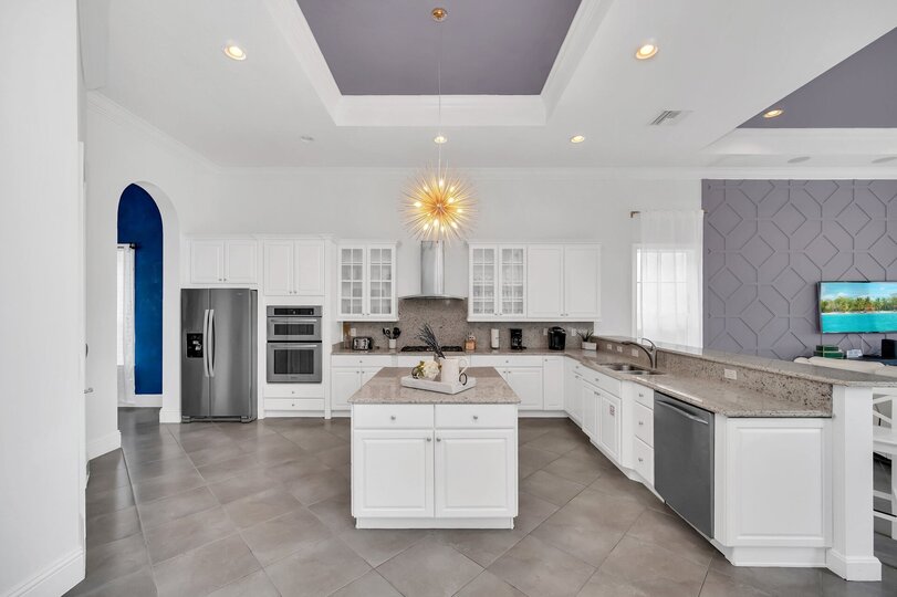 The open kitchen features modern appliances like a sleek 2-door fridge, oven, coffee maker, and more. With a central table at your disposal, meal preparation becomes a seamless and enjoyable experience.