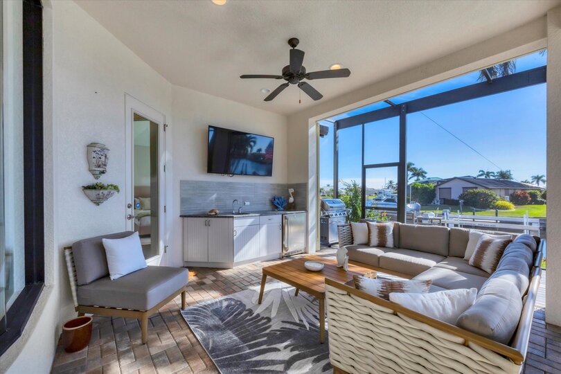 Gorgeous outdoor living space overlooking the sparkling private pool and canal beyond. Great for entertaining. This space features an outdoor kitchen, ample seating, grill, dining table that seats 8, and 50-inch Smart TV